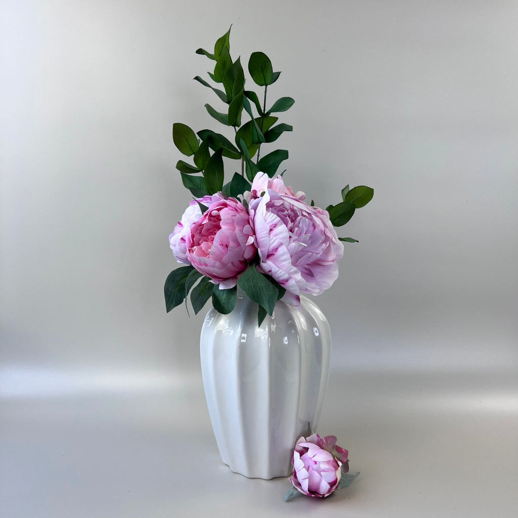 Carefully styled ribbed vase with pink and green floral arrangement 