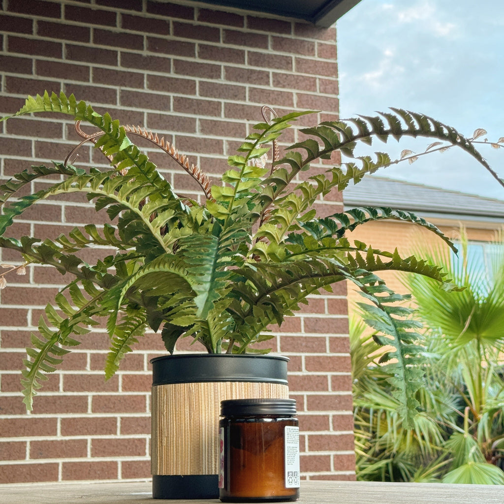 Artificial Boston Fern on an outdoor table in Bamboo pot