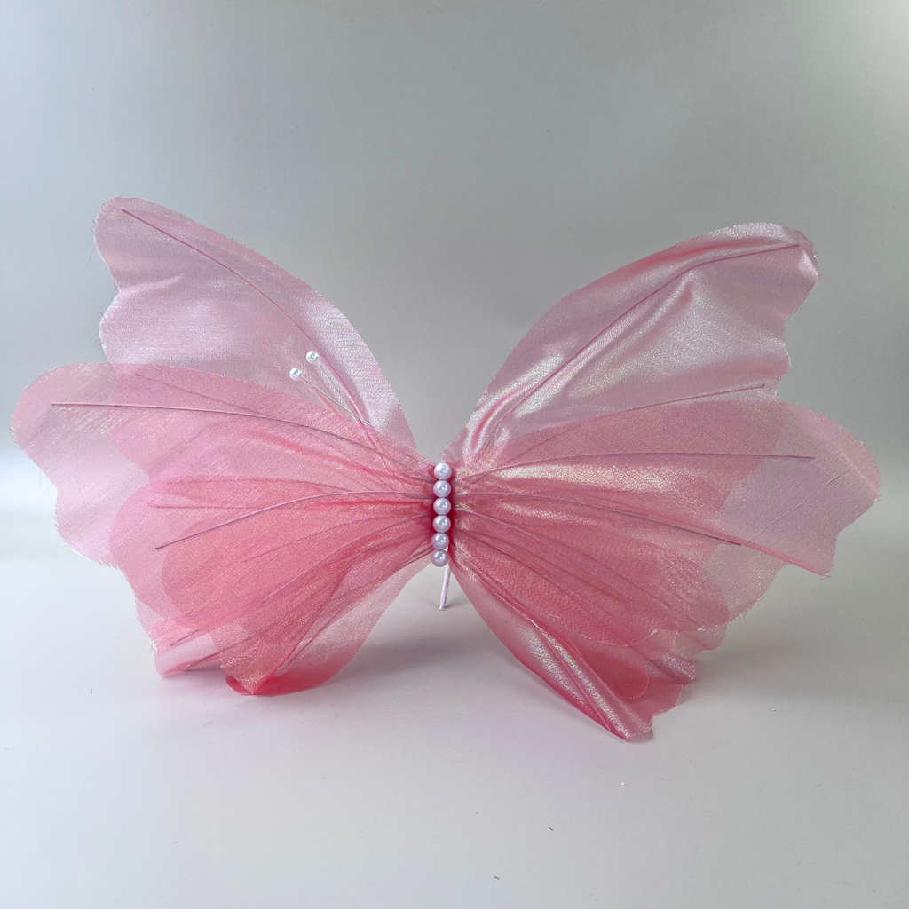 Pink butterfly with pearl accents on a beige background