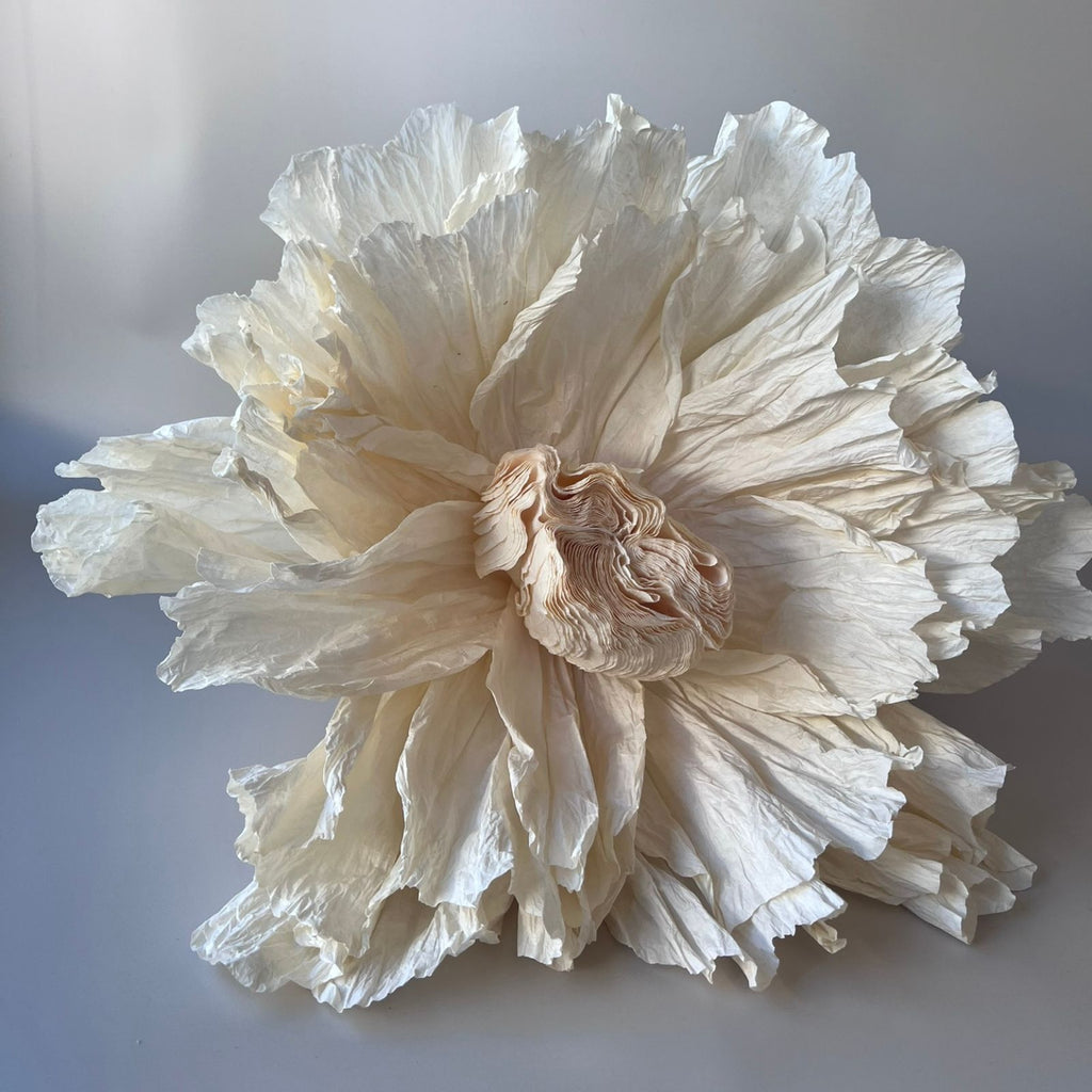 A large artificial ivory crepe paper flower with a layered design.