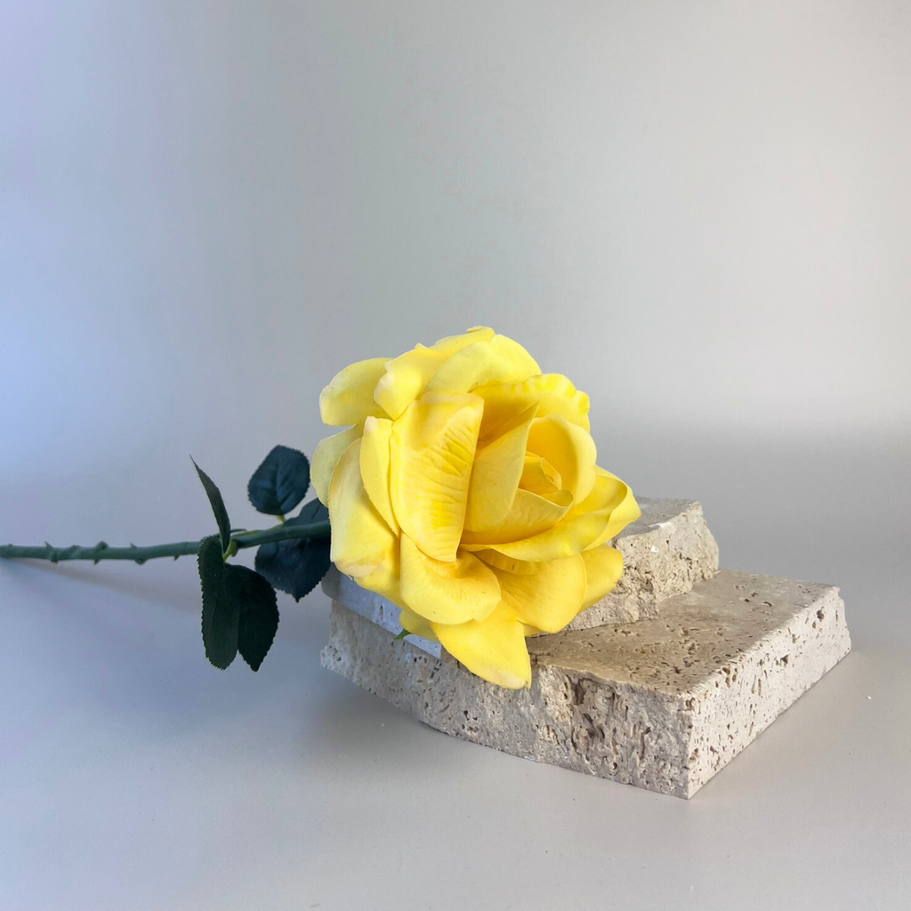 Yellow artificial rose positioned on top of props   