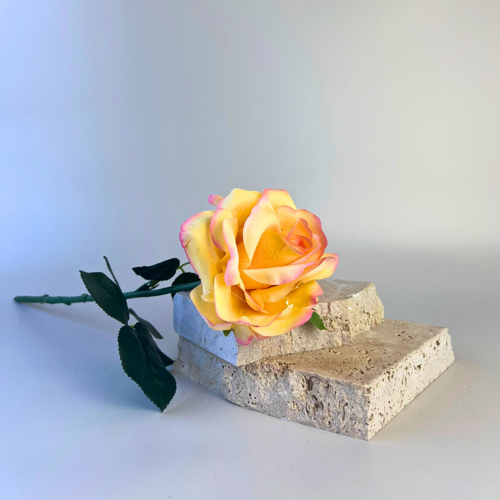 An artificial rose with petals in a stunning blend of coral hues