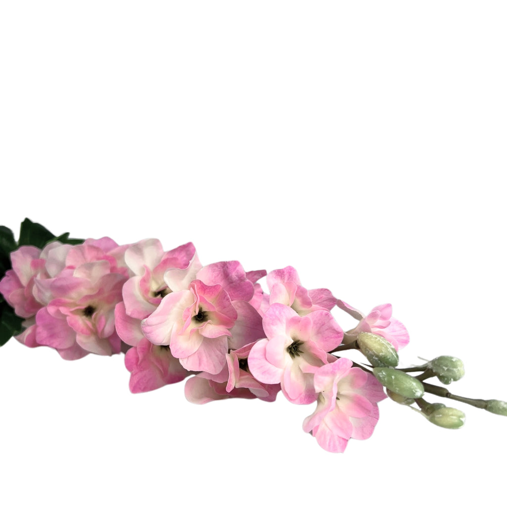 Close up of an artificial delphinium with soft pink lifelike blooms against a white background 