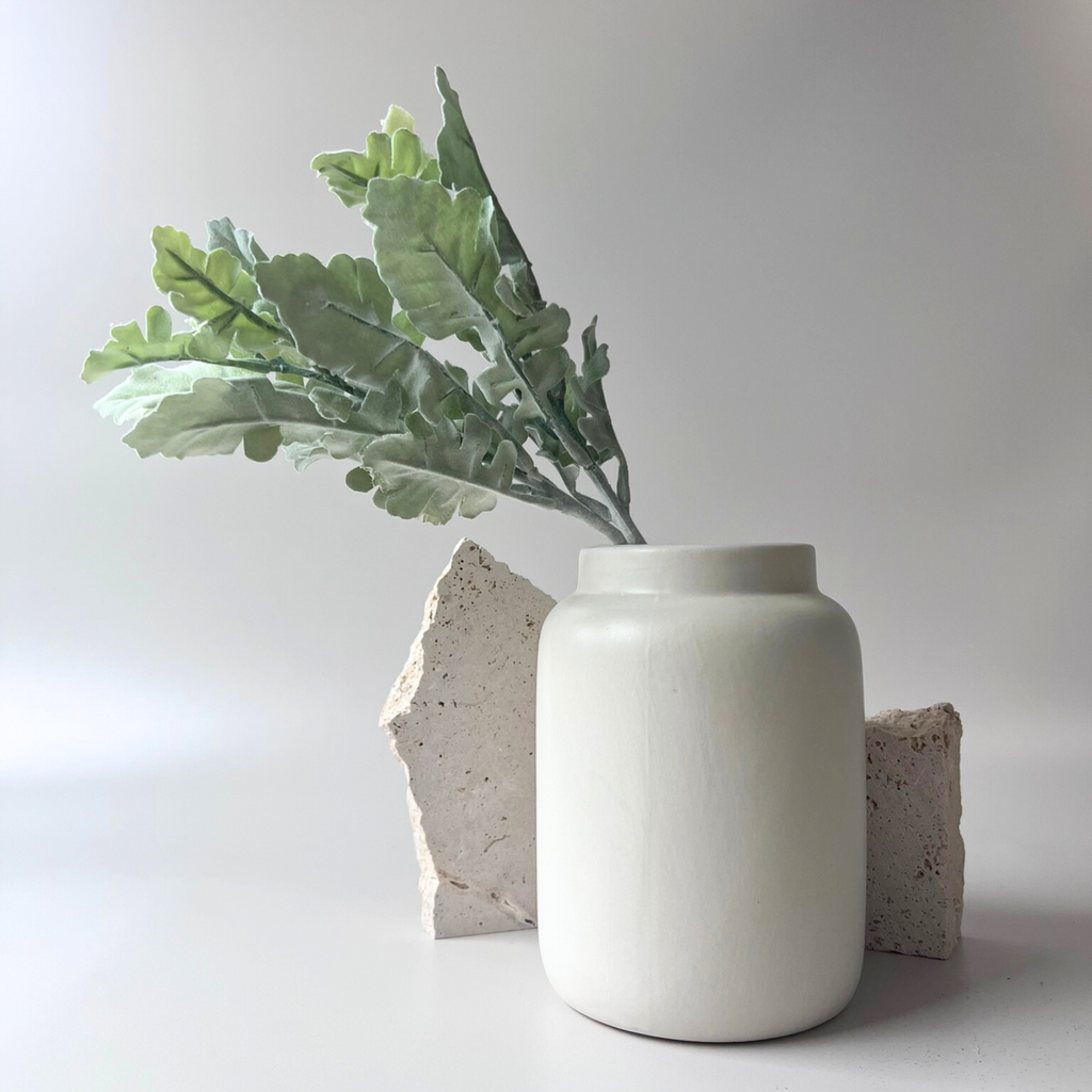 The artificial silver dust styled in a ceramic vase with rustic stones to compliment
