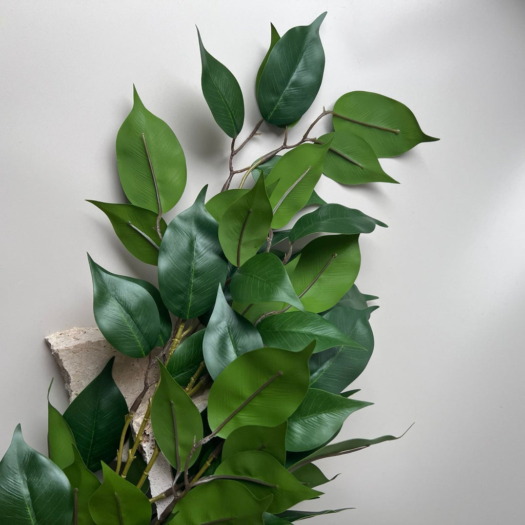 Close up of the artificial ficus branch on a cement block 