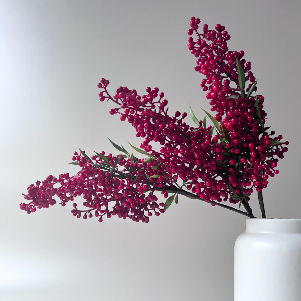 Close up of the styled red berry branches in a small size on a beige background 