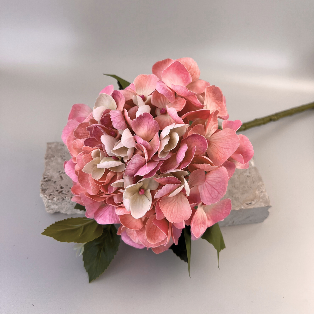 The Peach pink artificial Hydrangea in small styled on a concrete block 