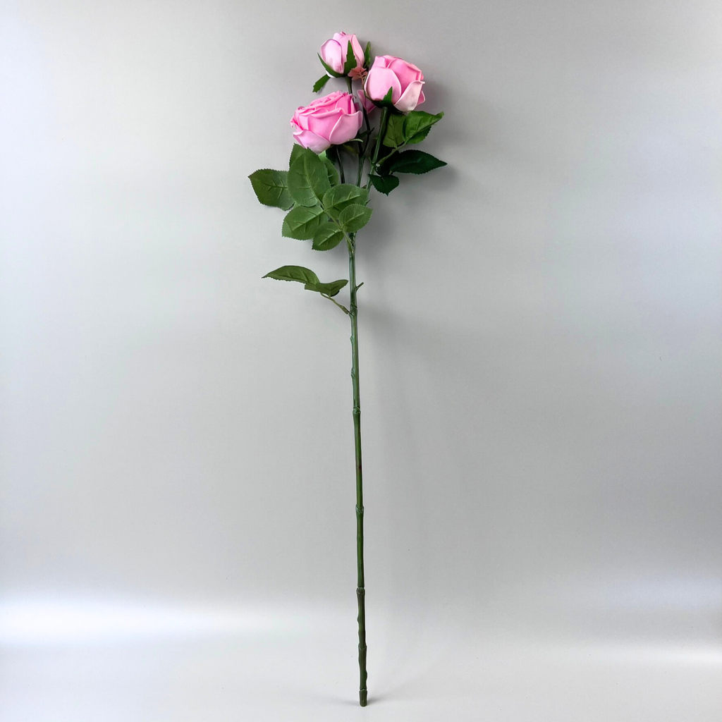 Artificial pink peony rose stem against a plain white background