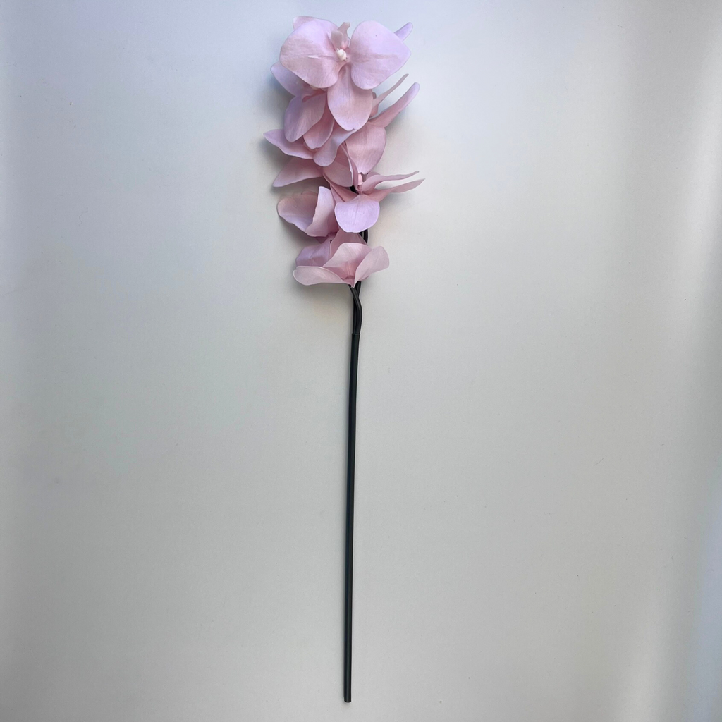Single artificial soft pink Phalaenopsis orchid against a plain background 