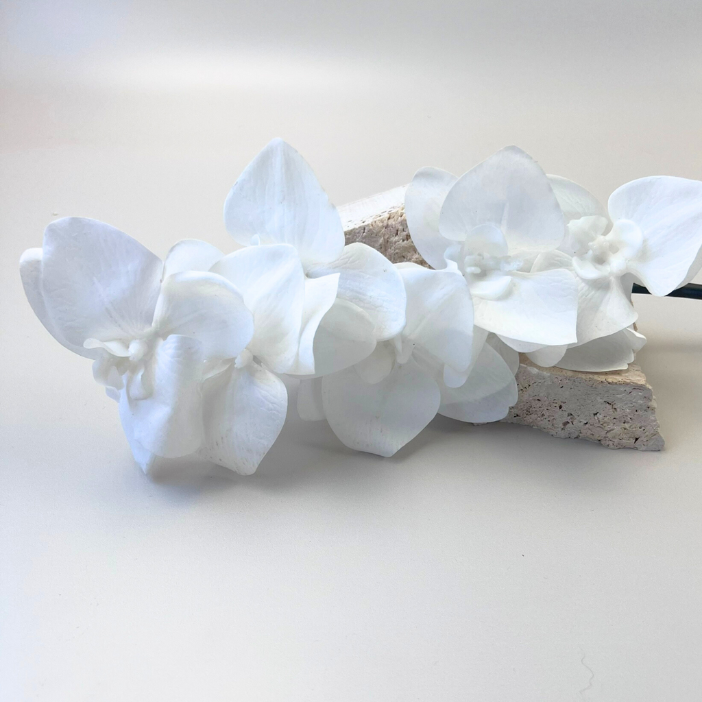 White Phalaenopsis orchids styled on pieces of cement against a beige background