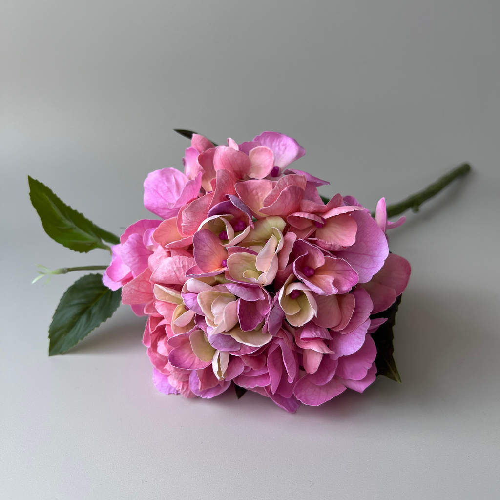 A lifelike artificial dark pink hydrangea flower with green leaves, suitable for floral arrangements.