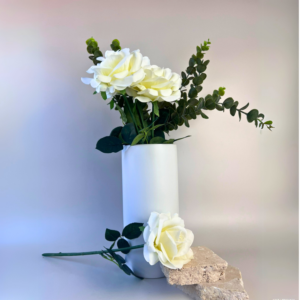White ceramic cylinder vase featuring beautifully styled flower and plant arrangement 