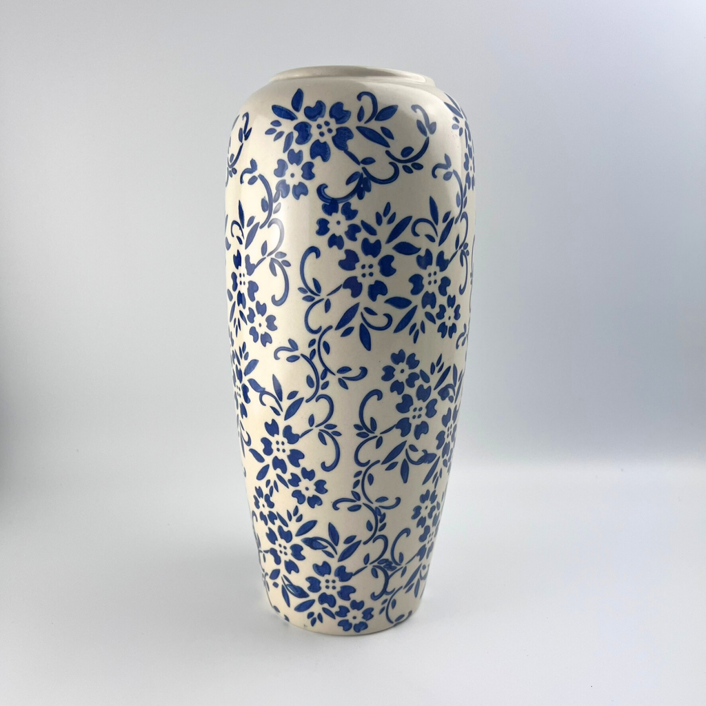White vase with blue florals on a plain beige background 