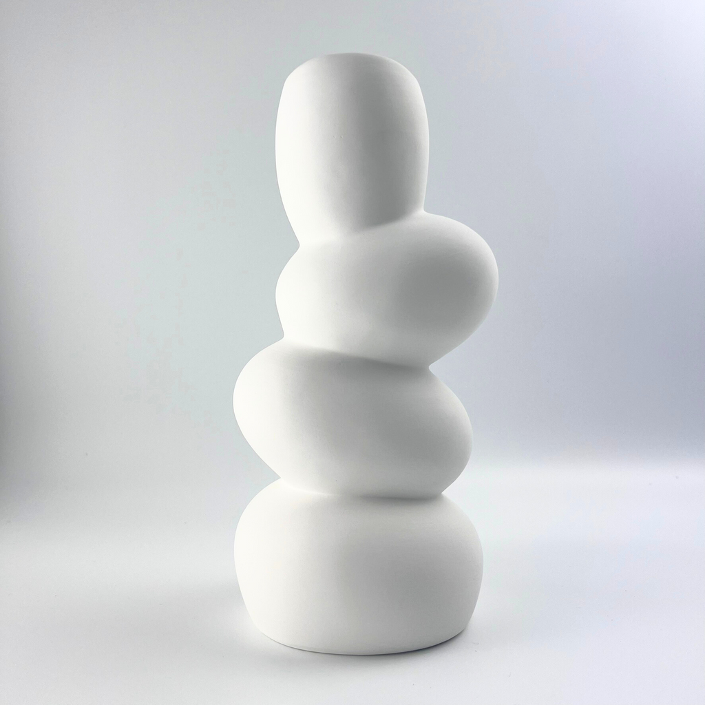 White ceramic vase with stacked cylindrical design on a beige background