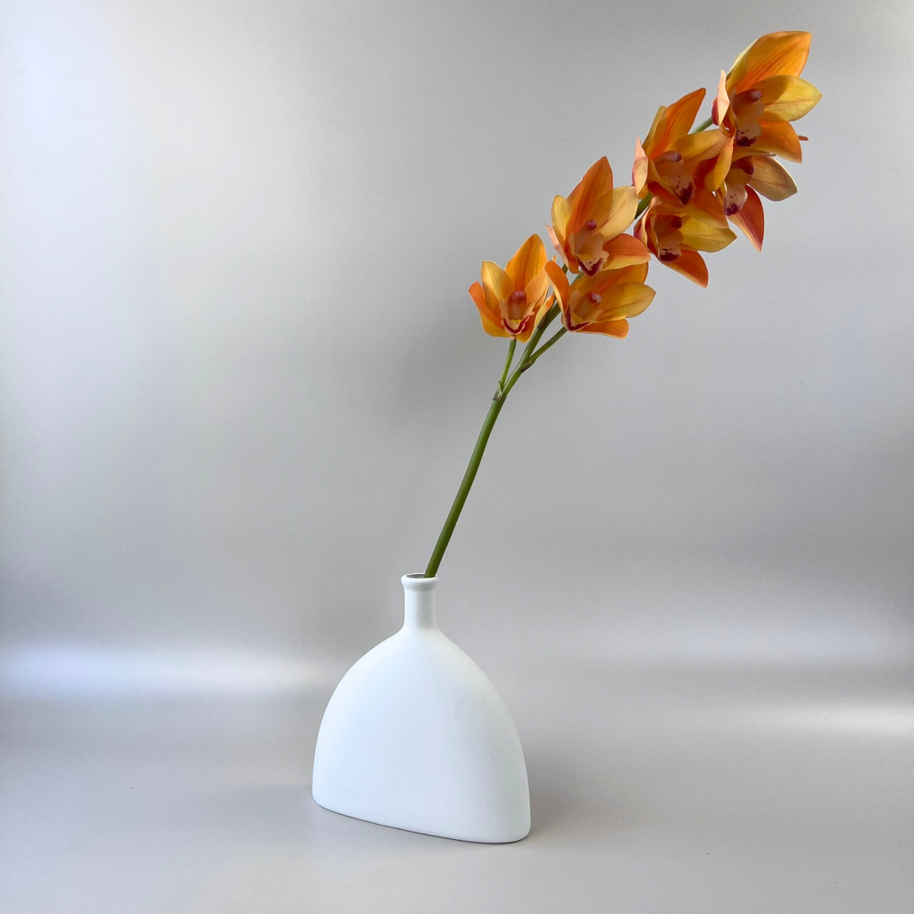 White dome-shaped vase with skinny vase neck styled with a vibrant orange floral stem 