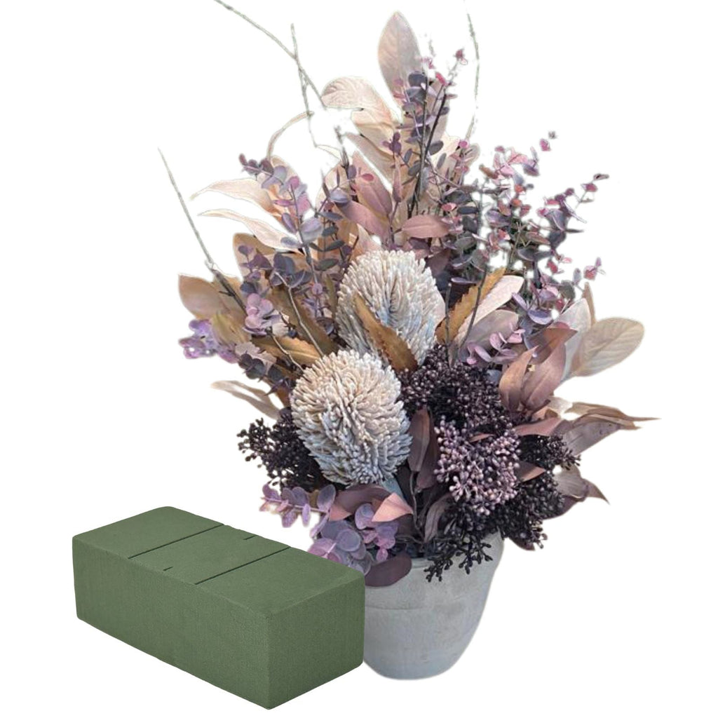 A Wet Floral Foam brick next to an Artificial Flower arrangement in a grey pot against white background